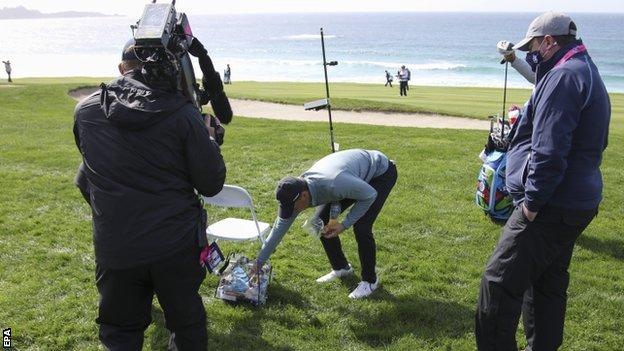 Jordan Spieth retrieving his ball from a volunteer's bag at the Pebble Beach Pro-Am