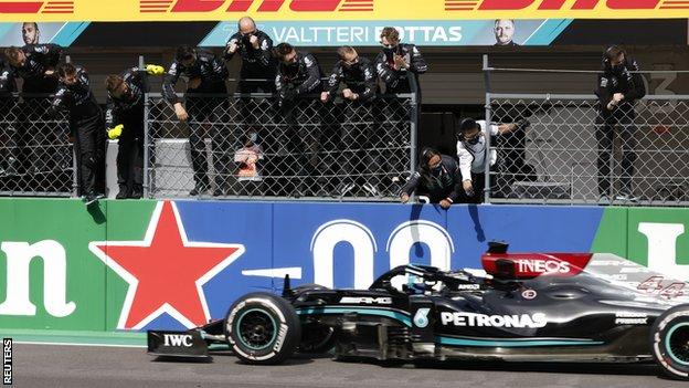 Mercedes crew celebrate as Lewis Hamilton drives past