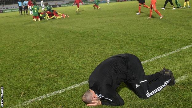 Algeria coach Djamel Belmadi sinks to the turf after their defeat by Cameroon in World Cup qualifying