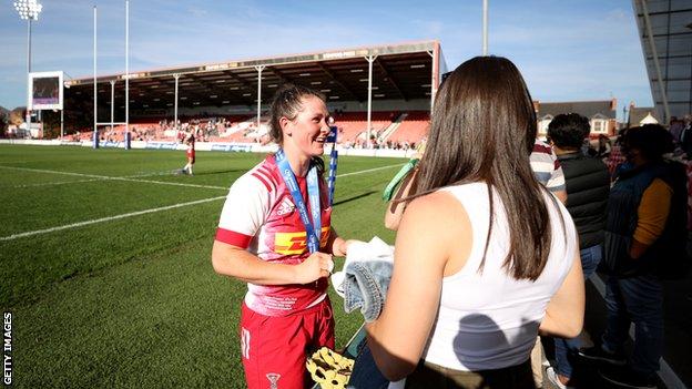 Emily Robinson wears a winners' medal and talks to fans