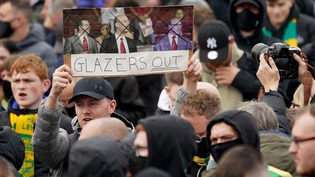 A Manchester United fan holds an anti-Glazer poster in the air
