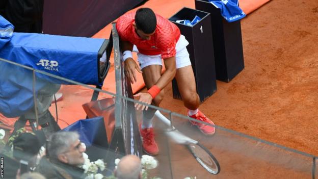 Novak Djokovic crashes into the clock at the side of the court