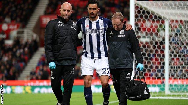 Nacer Chadli is helped off the pitch after being injured.