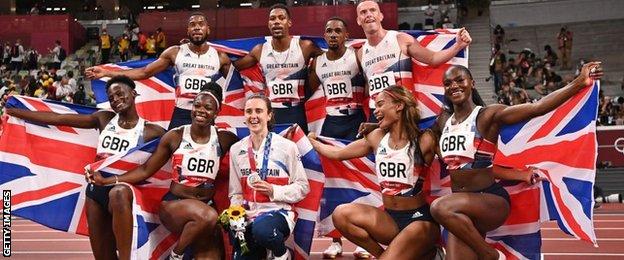 Men and women's relay teams pose with Laura Muir