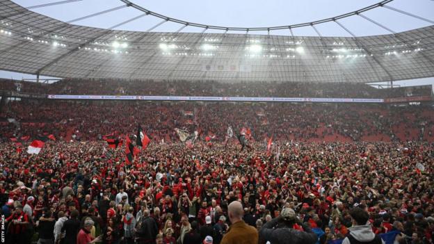 Leverkusen fans celebrate on the pitch