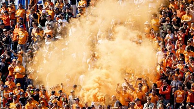 Orange flares go off in the stands