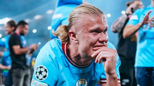 Erling Haaland crouches down, emotional, after winning the Champions League