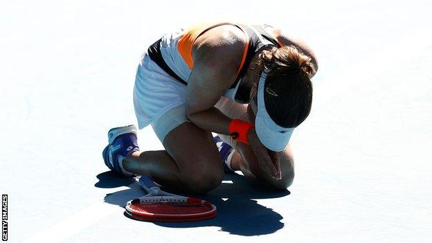 Alize Cornet sinks to her knees and holds her hands together after beating Simona Halep