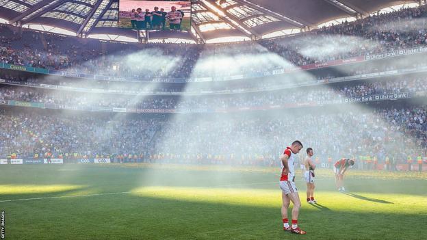 Les joueurs de Mayo ont l'air abattus alors que la lumière les éclaire depuis le dessus des tribunes de Croke Park.