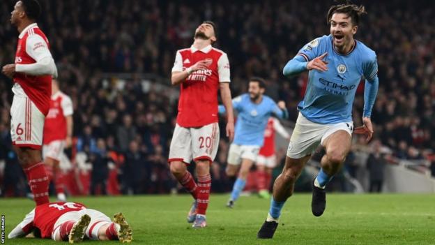 Jack Grealish of Manchester City celebrates as Arsenal players look disconsolate
