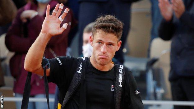 Diego Schwartzman waves goodbye to the Roland Garros crowd after losing to Rafael Nadal