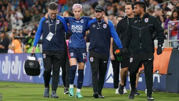 Medical staff help an injured Megan Rapinoe from the field in her farewell game