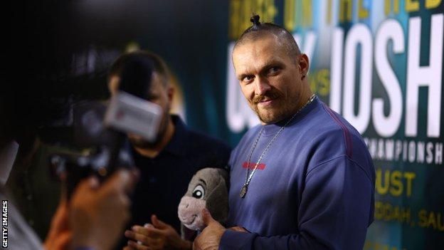 Oleksandr Usyk holds an Eeyore teddy at a media event