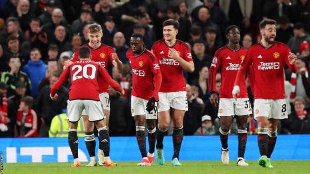 Manchester United players walk back to kick off after celebrating their fourth goal
