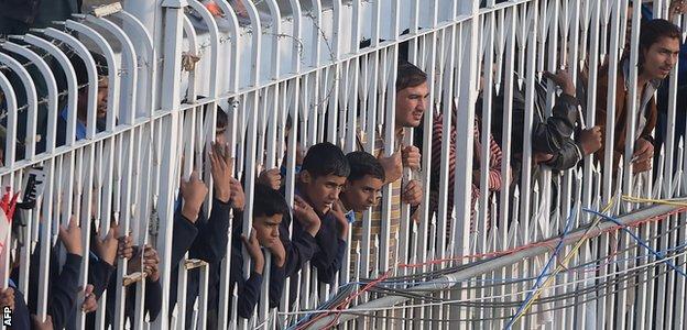 Fans peer through a fence