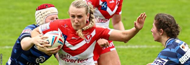 St Helens player Jodie Cunningham fends away a Wigan opponent during a derby in 2022