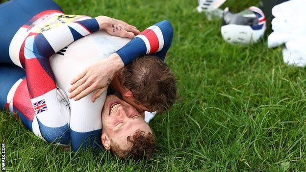 George Peasgood and Ben Watson hug on the grass, celebrating their medals