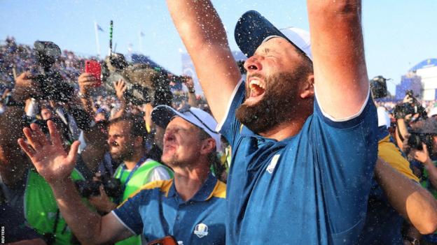 Jon Rahm celebrates Europe winning the Ryder Cup by raising his arms in the air