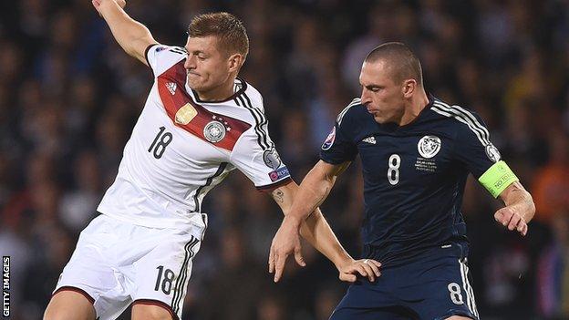 Toni Kroos of Germany is challenged by Scotland captain Scott Brown