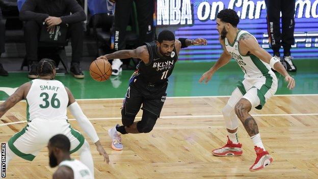 Brooklyn Nets guard Kyrie Irving dribbles the ball past two Boston Celtics players