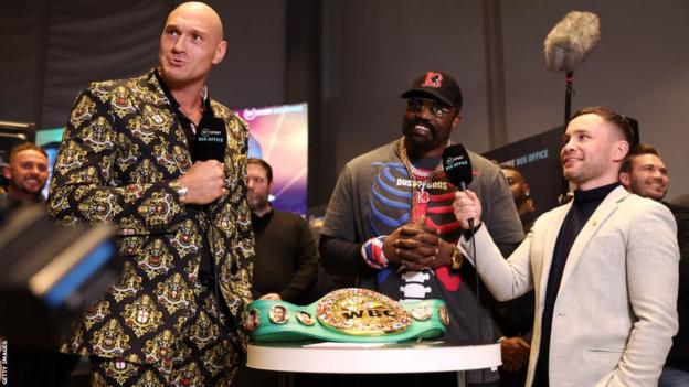 Tyson Fury and Derek Chisora smile while being interviewed by Carl Frampton