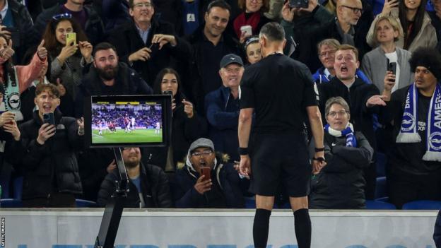 Referee Andre Marriner checks the pitchside VAR show   earlier  awarding Brighton a punishment  against Manchester United