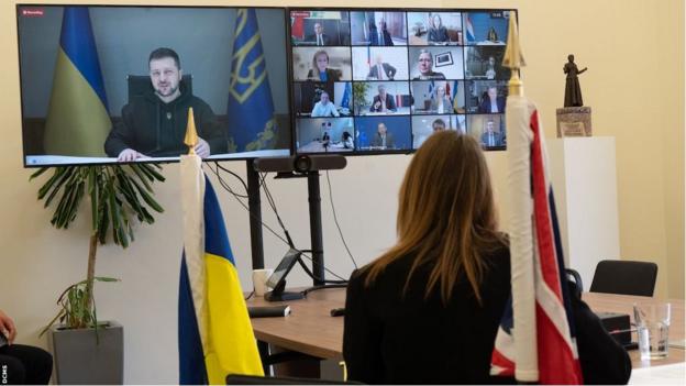 Ukraine president Volodymyr Zelensky speaks to a summit of 30 nations via video link, with UK culture secretary Lucy Frazer sat in the foreground