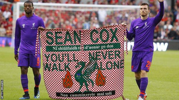 Georginio Wijnaldum and Andrew Robertson carry a flag on the pitch in support of fan Sean Cox