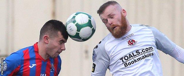 Mark Kelly of Ards in action against Ross Clarke of Crusaders