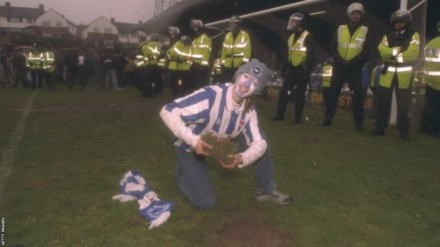 Een fan van Brighton poseert met gras van het veld na de laatste wedstrijd van Brighton op Goldstone Ground in 1997.