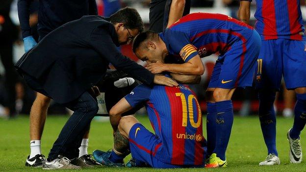 Lionel Messi (number 10) sits on the pitch injured