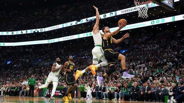 Golden State Warriors player Stephen Curry drives for the basket as Jayson Tatum of the Boston Celtics tries to challenge him