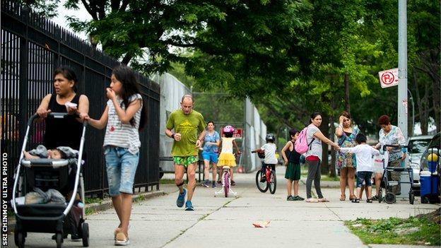 A competitor runs through the crowded sreets of Queens