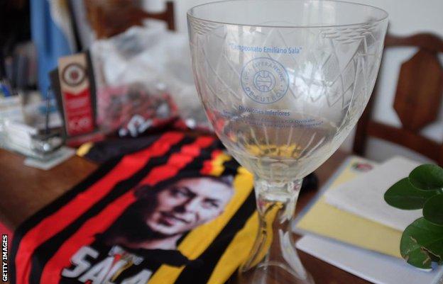 Commemorative cup, with Liga Emiliano Sala branding, and San Martin shirt paying tribute to Sala