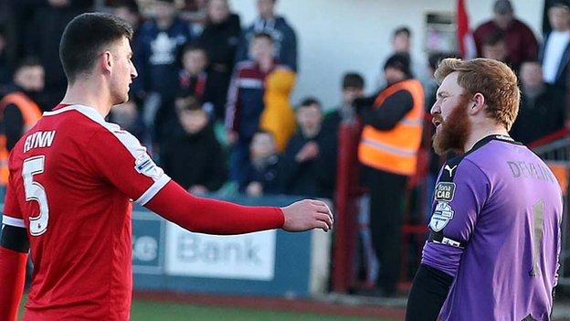 Cliftonville's Johnny Flynn asks for the goalkeeping gloves from Conor Devlin after the Reds number one was sent off during the cup quarter-final