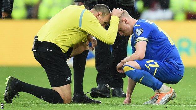 Spanish referee Antonio Miguel Mateu Lahoz consoles Ukraine's Oleksandr Zinchenko after Wales' victory