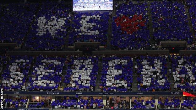 Fans hold up pieces of card with the message 'We love Serena'