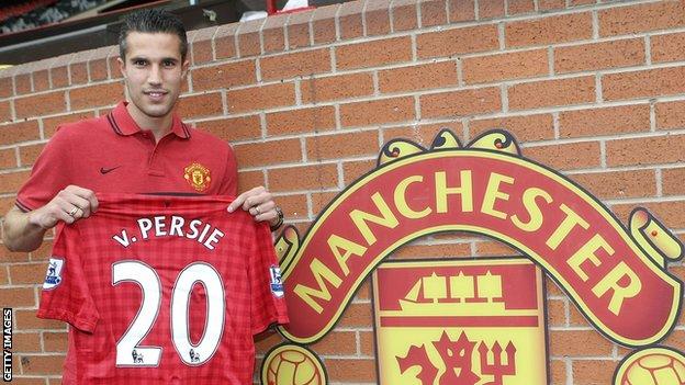 Robin van Persie holds up a Manchester United shirt bearing his name after signing for the club