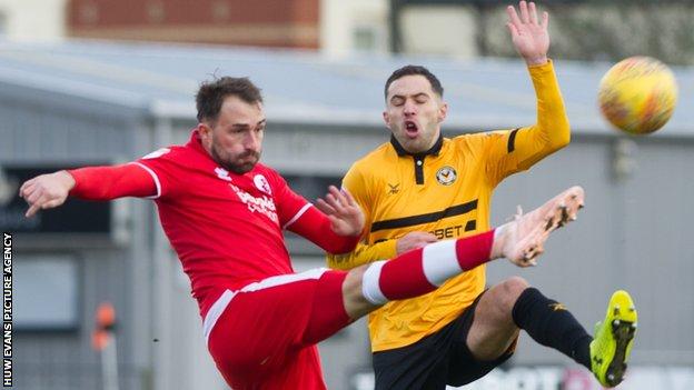 Josh Payne of Crawley Town clears under pressure from Robbie Willmott of Newport County
