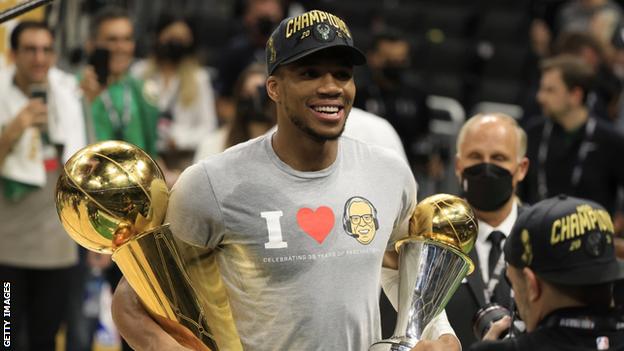 Giannis holds the NBA title alongside his Finals MVP trophy