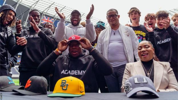 Daniel Akinkunmi puts on an Oklahoma cap on his 'commitment day'