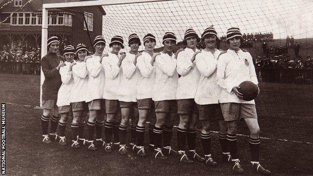 The Dick, Kerr Ladies football team in line on a goal line, with Lily Parr at the front holding a football