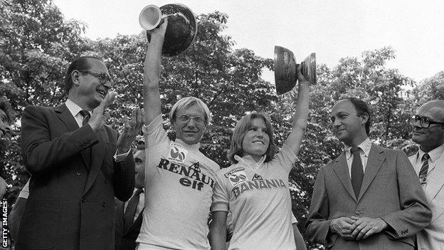 1984 Tour de France winner Laurent Fignon raises the trophy alongside Tour de France Ferminin winner Marianne Martin on the podium