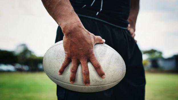 Un homme tenant un ballon de rugby