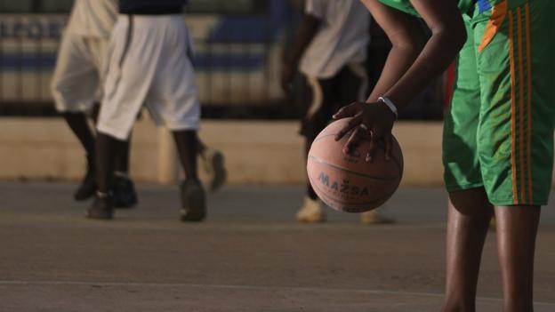 Una mujer sostiene una pelota de baloncesto en sus manos