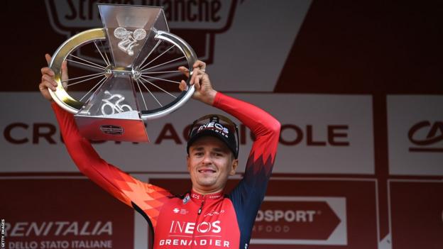 Britain's Tom Pidcock holds up the Strade Bianche trophy after winning the one-day classic