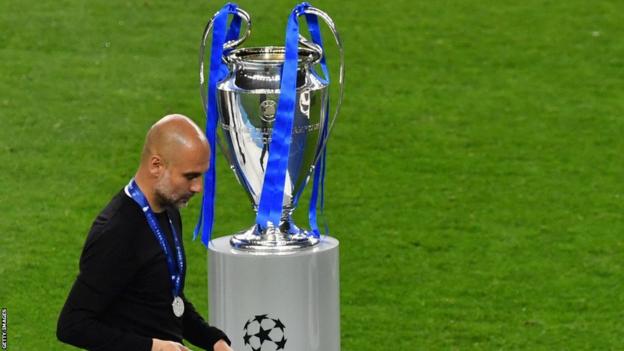 Pep Guardiola walks past the Champions League trophy