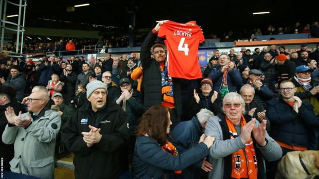 Luton fans hold up a number four Tom Lockyer Luton shirt
