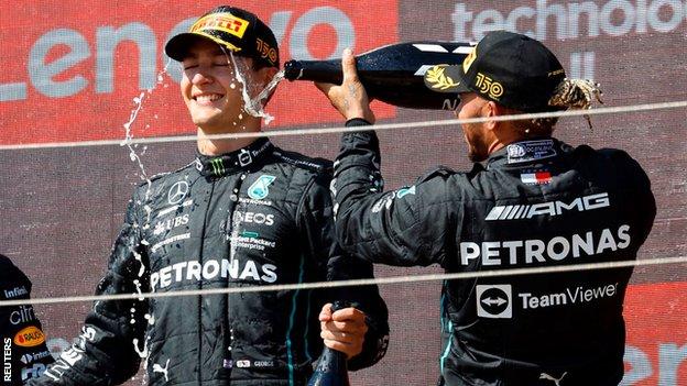 Lewis Hamilton pours champagne over George Russell on the podium