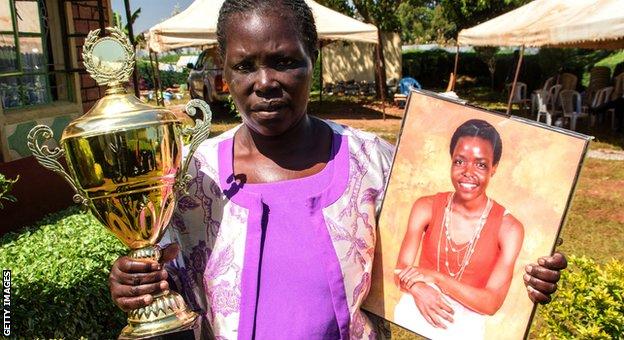 Dinah Tirop with a portrait of Agnes Tirop and a trophy won by her daughter